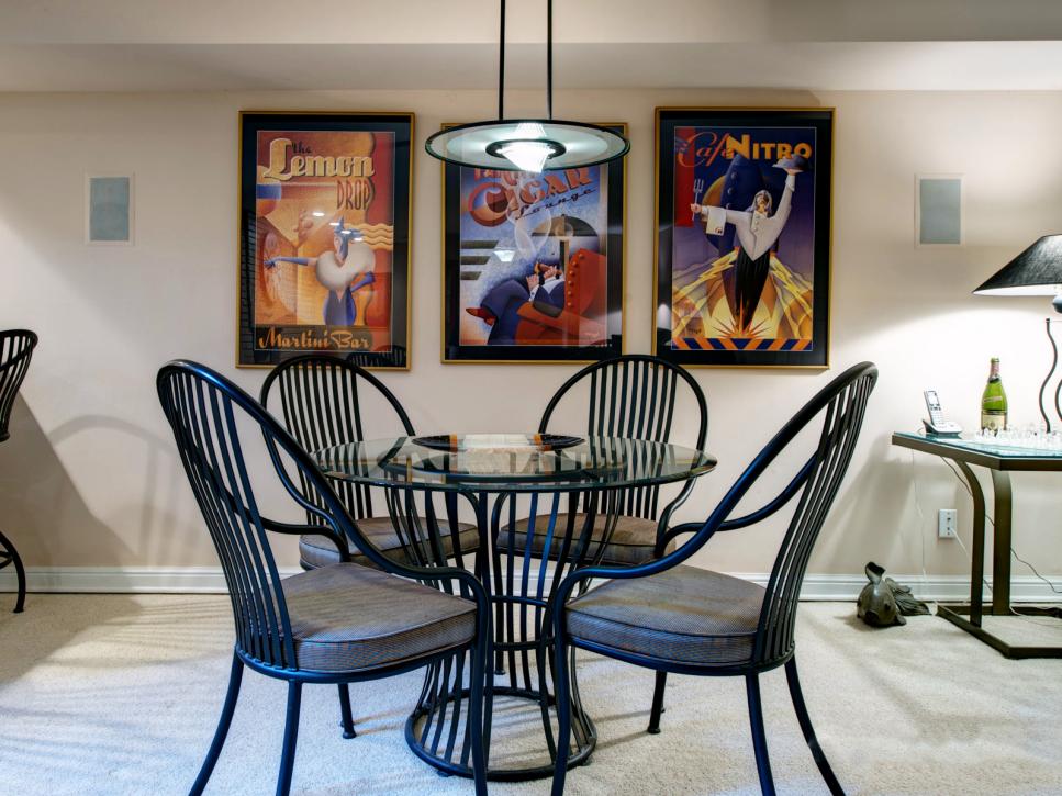 Round Table With Black Chairs In Front of Framed Prints