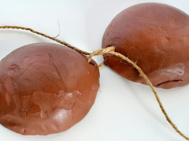 Place "coconuts" side by side and turn so they each have a hole facing in and a hole on top. Cut twine and slide through inner holes to connect coconuts. Cut two more long pieces of twine and string through top holes to serve as halter-top straps.