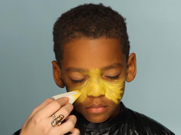 To create a base for your lion makeup, begin by dampening a sponge then picking up some of the yellow face paint. Tip: When using dry face paints, be sure to get sponge or brush wet before dipping into paint. Have child close their eyes, then apply yellow paint to the center of their face and blend out.