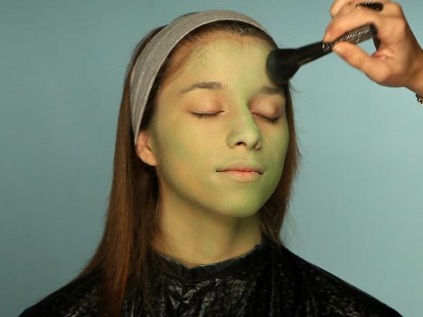 To turn your tween into a hip Frankenstein for Halloween, begin with a green cream makeup base. Cover entire face using a sponge. Using a fluffy blending brush and a light green eye shadow, cover the face everywhere the green cream makeup was applied. Add a touch of pink blush to apples of cheeks. Define eyebrows with brown or gray eyebrow pencil. Cover eyelids with a purple or mauve eyeshadow and blend up to crease. Use a slightly lighter shade at the halfway point and blend the colors together. For older girls who are comfortable wearing eye makeup, add black liner and mascara to top and bottom lashes to define them and make the eyes appear larger. Add stitch lines and bolts.