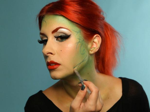 With shimmering green eyeliner pencil, add swirly vines stemming from the hairline, reaching toward the center of the face without going too far into your cheeks.