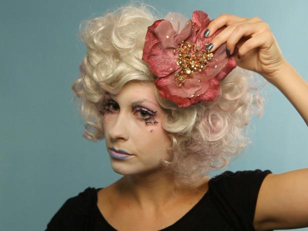 Get the look with a wig, or curl, tease and pin your own hair to mimic Effie's short couture style. Pick up a can of temporary haircolor spray in pastel shades to make your hair distinctly Effie. Finish the look with an oversized flower clip.