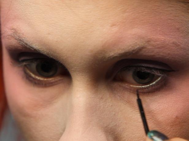 Define eyes by very thinly lining them with a black liquid eyeliner. Create a tiny winged edge, then add just a whisper of a line underneath the eye as well, staying as close to the lash line as possible. The goal is just to add a bit of definition, so apply with a light hand.