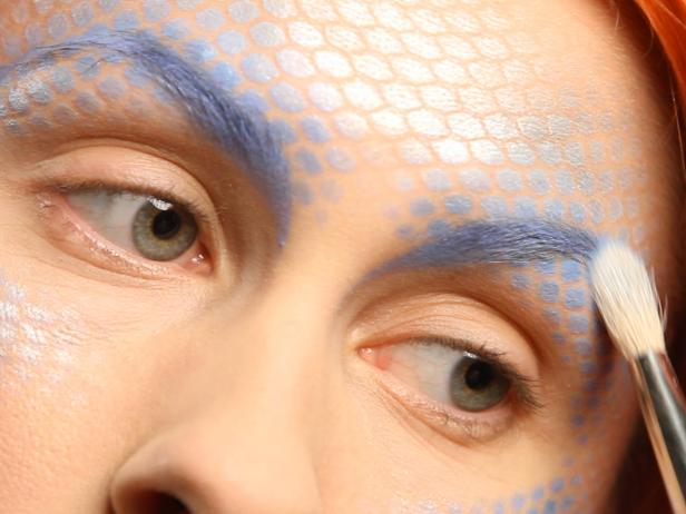 Detail eyebrows with a brush and blue creme foundation, then set it with a touch of shadow.