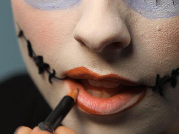 Line and fill in lips with red pencil. To make lips look asymmetrical, line outside of lip line on one side of top lip and opposing side on bottom lip.