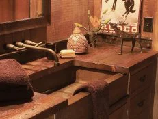 The bathroom sink offers custom cabinetry made from recycled materials and a hammered copper sink. Western artifacts complement the setting.