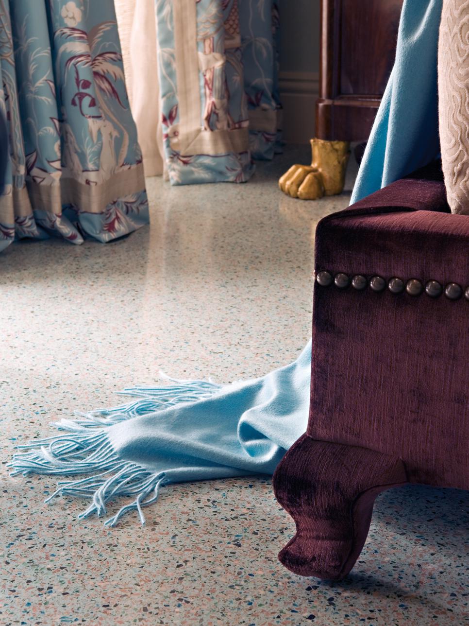 Blue Throw & Leg of Upholstered Platform Bed on Speckled Floor