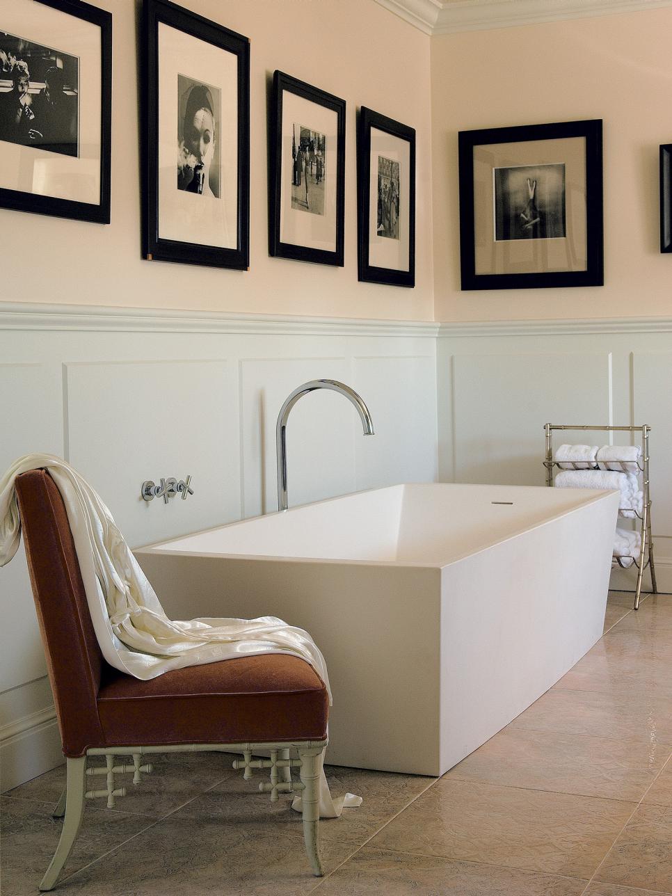 White bathtub with chair and photos on wall