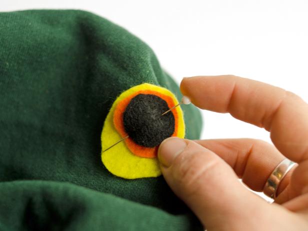 Pin the layered felt cutouts one on each side of hood. Sew with black thread to secure on the hood.