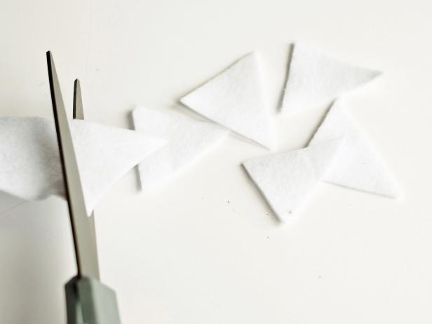 Make dinosaur teeth by cutting white felt into triangle pieces. Arrange teeth on top with about half an inch gap between each one.