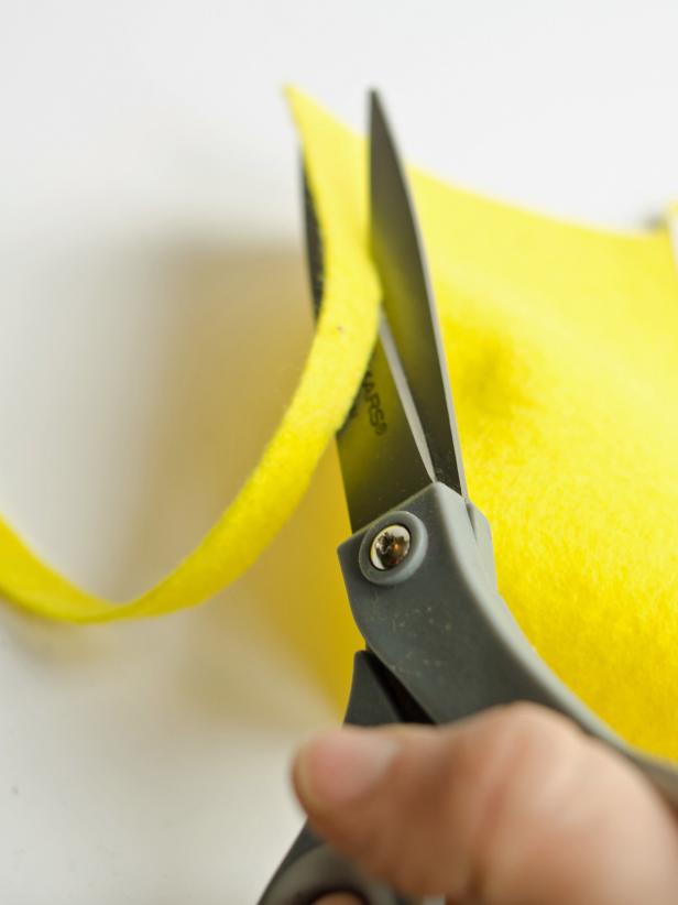 Out of the yellow felt quarter, cut several three quarter inch strips to use as gums. Position yellow strips inside cut in hood hem.