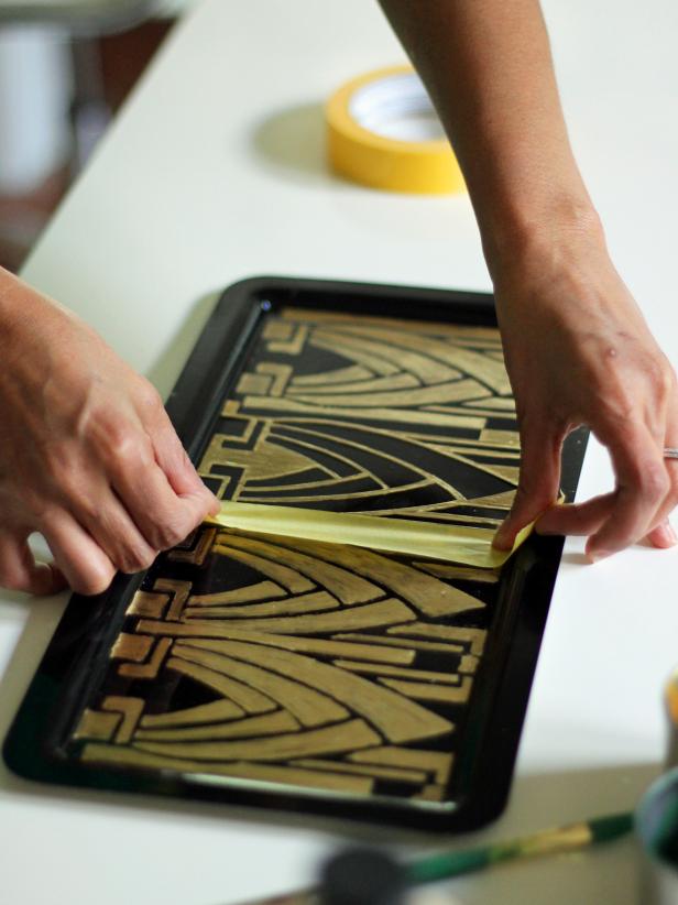 Letting the paint dry completely on each section of the tray before removing the stencil and painter's tape is step 4 in creating an Art Deco vanity tray. If you pull the tape up before the paint is completely dry, the tape might pull the paint from the surface of the tray.