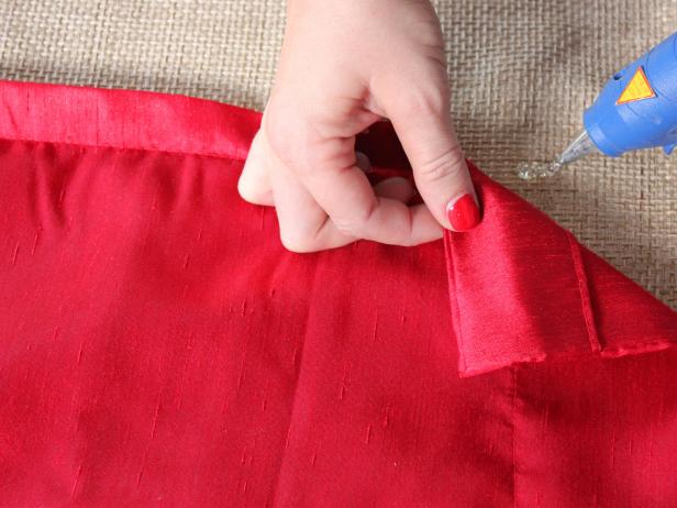 Affixing drapery panel cuts with glue gun for a no-sew shower curtain.
