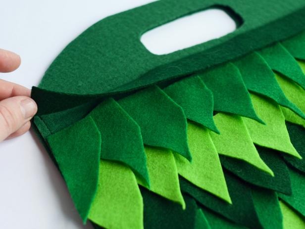 Arrange felt leaves in rows, alternating colors, overlapping leaf points. Cut a strip of dark green felt 1/2" thick and as wide as bag. Dry-fit all pieces to ensure the desired look is achieved.