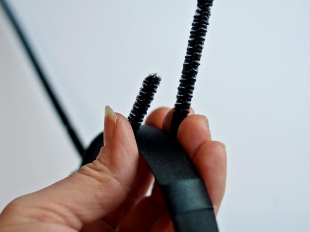 Wrap one end of a black pipe cleaner around headband and twist to secure. Repeat with second pipe cleaner and slide each to appropriate position for antennae.