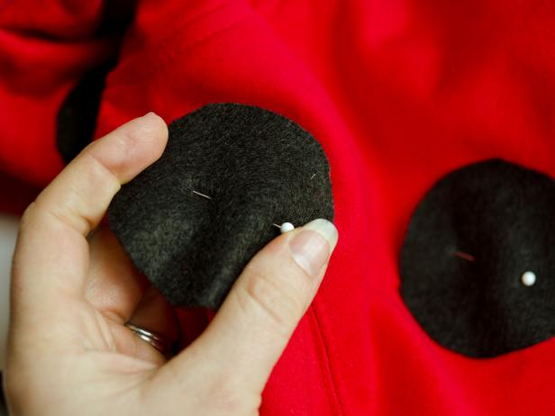 Pin spots randomly onto front and back of sweatshirt. Sew around perimeter of each spot to secure then remove pins and trim threads.
