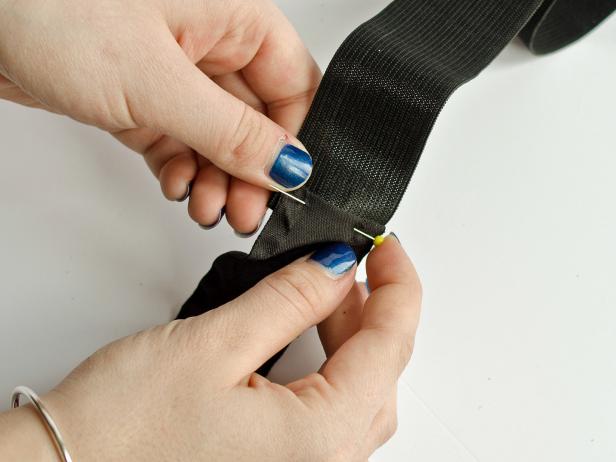Once the black ribbon has been folded over each end of the elastic band, Step 1C in making a waistband for the witch's costume is to pin the ribbon to secure it onto the elastic band. Sew in place.