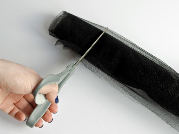 After cutting the black tulle into pieces that are approximately 25 to 30 inches wide with sharp scissors, Step 2C in making a tutu is to cut the tulle in three-inch sections once it is rolled and measured.