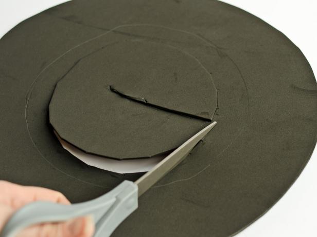 Step 5C in making a witch's hat is to use a scissors and cut about 1/2" inside the base of the cone's traced line and remove the inner circle. This is done after the cone is set and centered on the top of the circle and it is traced with a pencil around its base.