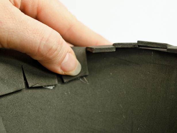 Step 5E in making the brim for a witch's hat is to apply dabs of glue inside the base of thecone and press the cut tabs into the glue to secure the cone to the hat's brim. Hold the glue in place until it cools. Repeat the process until all tabs are glued to the hat's interior.