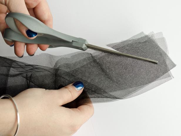 Step 2E in fashioning a tulle skirt for a child's Halloween costume is to cut the ends of the tulle at an angle to emphasize a jagged look. This step is done after you have cut tulle strips in half by folding them lengthwise and cutting them at the fold.