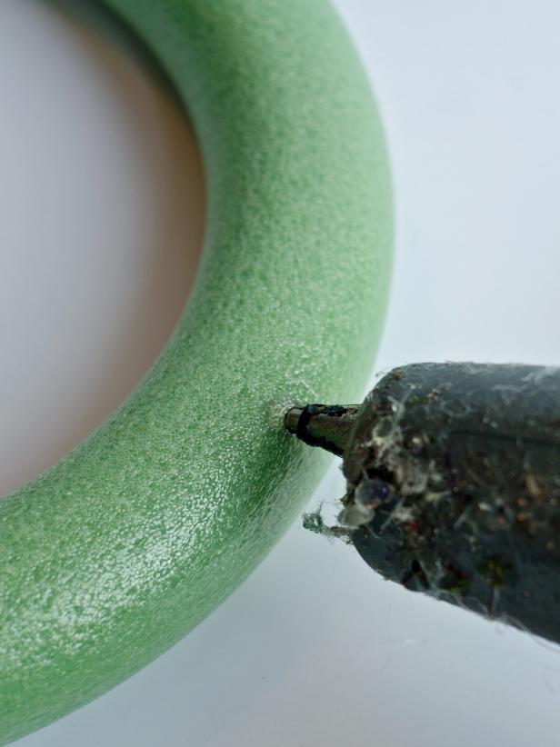 Preheat hot glue gun. Apply a small dab of hot glue to foam wreath.