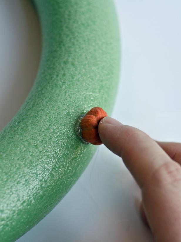 Preheat hot glue gun. Apply a small dab of hot glue to foam wreath. Immediately press a dried putka pod into hot glue and hold into place until glue cools.