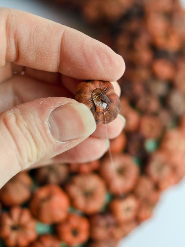 Place a small dab of hot glue on underside of a pod and press it into a place on the wreath where form is showing through.