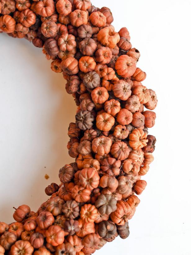 Place a small dab of hot glue on underside of a pod and press it into a place on the wreath where form is showing through. Continue to apply pods to fill gaps until wreath form is no longer visible.