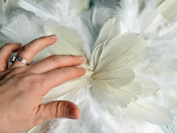 Step 7E in creating feathered angel or fairy wings is to flip the wings over and cover the feather points on the back side with any remaining fluffy feathers, adhering them with hot glue. Note: Since this side will not be visible when worn, feathers don't need to cover all of the foam core. Have your child try on their wings and if all visible bits of foam core are covered, you're done.