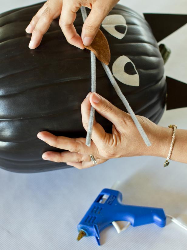 Cut three pipe cleaners in half and use hot glue to attach them to the pumpkin under the edges of the felt nose