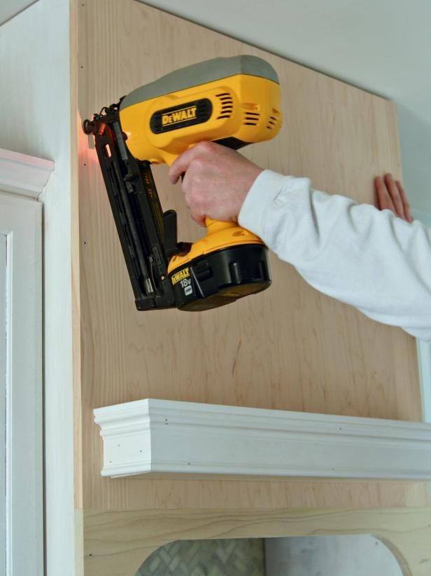 To attach a front panel for a custom range hood project, fit the front panel onto range hood and nail in place with finishing nailer.