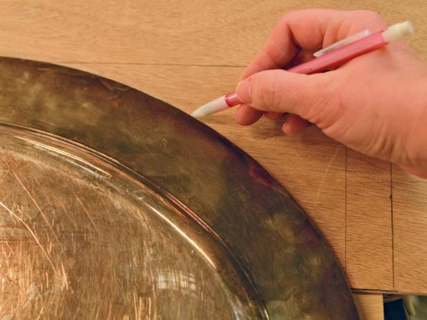 Using a combo square, mark off top and sides of arch on 1/4" MDF or luan to make a template. Leave approximately 2 inches on each side of arch and 2 inches from top of poplar board to allow for pocket holes. Use an oval tray or platter as a template for the curve.