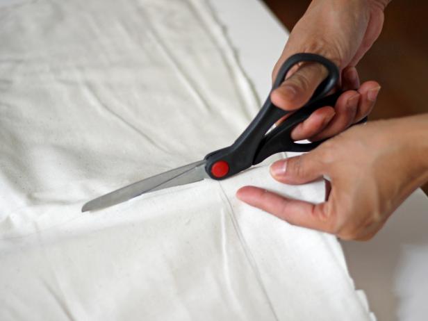 Step 3B in creating a feathered back vanity chair is to draw and cut fabric to fit the size of your chair. Use a pencil to trace the inside chair back onto muslin fabric. Cut the fabric with scissors.