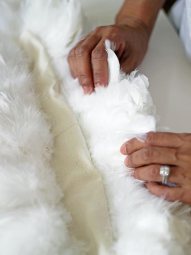 Step 4B in creating a vanity chair with feathers is to sew lengths of feathers to the fabric shape, starting from the top to the bottom. This creates rows of feathers on the fabric that can be placed against the back of the chair.