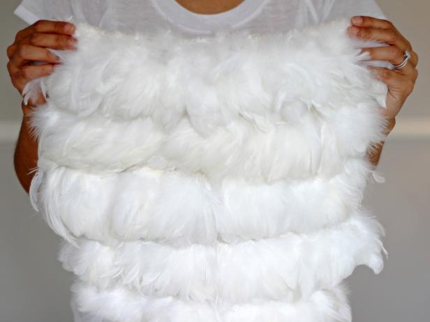 Once the feathers are sewn onto the fabric in rows, hold it up and examine the finished piece before you attach the fabric to the chair. Make sure the fabric will fit against the back of the chair before starting the gluing process.
