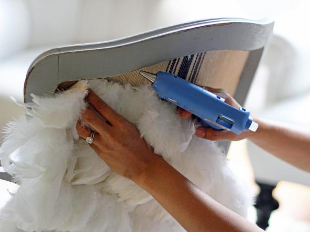 Step 5 in embellishing a vanity chair with feathers is to glue the fabric onto the chair. Using a glue gun, hot glue the top and bottom of the chair shape fabric onto the chair back, making sure it is fully covered by the fabric.