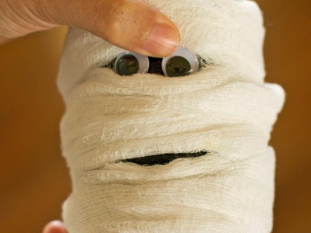 To create a place for the googly eyes, pull the cheese cloth apart as shown in step 6 and use hot glue to attach them to the can.