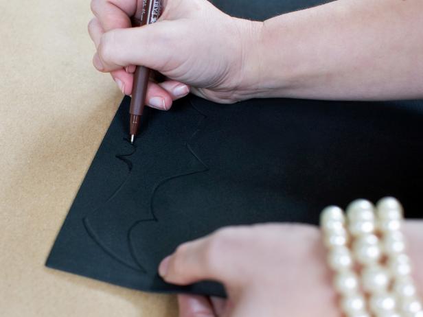 Trace or freehand the silhouette of a bat onto craft foam with black pen or marker then cut out silhouette with scissors. Repeat the process to make multiple bats in assorted sizes.