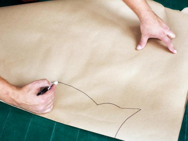 Place a sheet of brown kraft paper onto a flat, level surface then fold it in half. Freehand the silhouette of an owl to the size and scale you'd like using a pen or marker