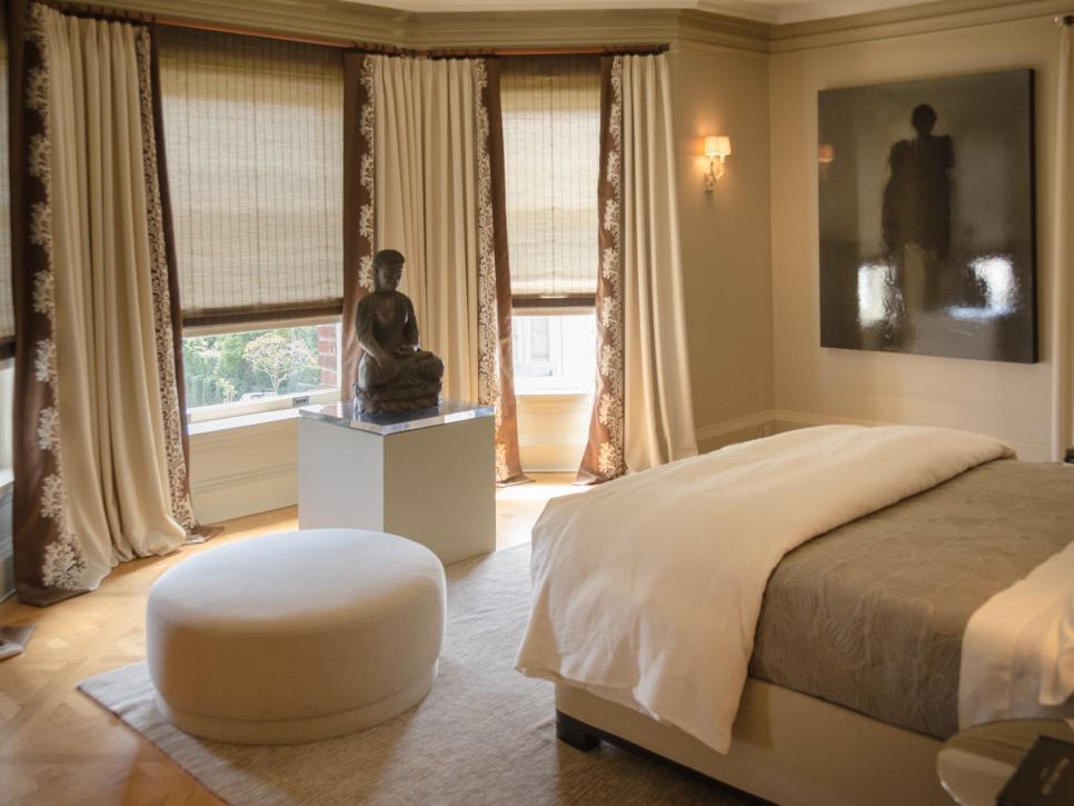 Taupe Bedroom With Cream Drapes, White Ottoman and Stone Statue