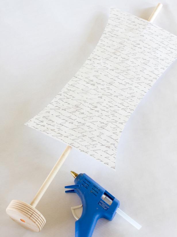 Cut along the arched lines with scissors, then remove tape and hot-glue the paper "sails" (patterned sides facing out) to the wooden dowel, leaving two inches of dowel visible above the sails.
