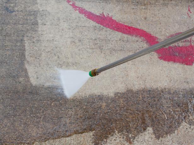 Pressure wash concrete by holding down spray handle, working your way back and forth from one side of concrete surface to the other.