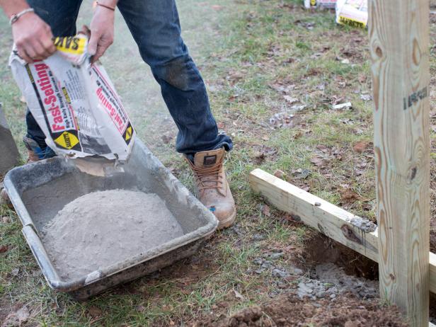 Open and pour bags of cement into mixing tub. Next, add water, then mix using shovel. Once liquified, use shovel to fill each of the two holes with cement.