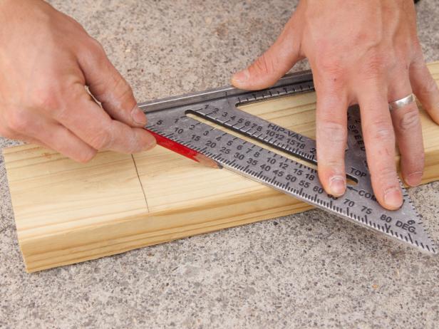 A ruler and a pencil are used to measure and mark a piece of wood.