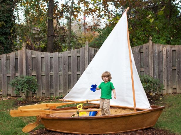 This backyard features a sandbox sailboat ready for adventures.