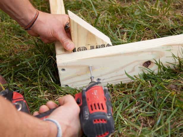Using exterior coated wood screws, secure one spike into each of the four corners of the box frame.