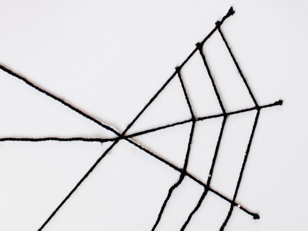 Continue gluing yarn pieces to cross points until the yarn completely circles around to form the web.