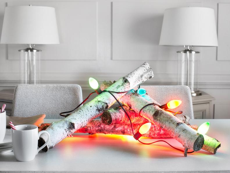 Birch log centerpiece wrapped in holiday string lights