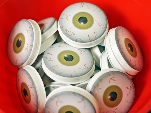 Print the eyeball template (http://hgtv.sndimg.com/HGTV/2013/07/19/original_Sam-Henderson-Snake-Eyes-template.pdf) onto six sheets of label paper. Cut out the design using scissors or a circle cutter. Remove backing from label and apply one eyeball to the flat back of each tube cap.